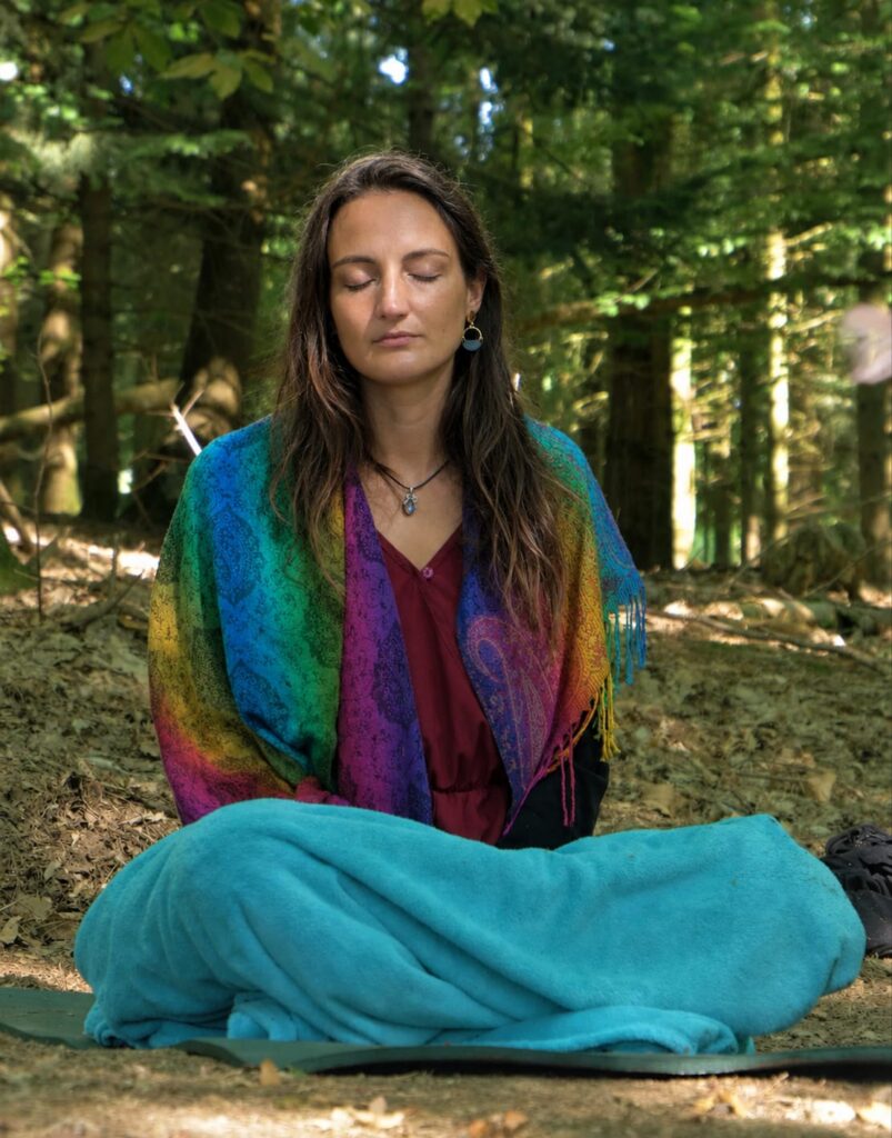 Femme méditant les yeux fermés en forêt, lors d’un cercle méditatif